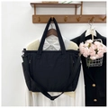 Detailansicht der schwarzen gesteppten Nylon-Einkaufstasche an einer hölzernen Garderobe - Schwarz