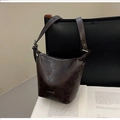 Detail of vintage brown bucket bag with adjustable strap and embossed logo on soft leather - No Pendant / Ebony