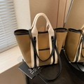Khaki canvas tote bag with cream handles and black leather trim in minimalist setting - Khaki