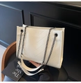 Detail view of cream leather tote bag featuring chevron quilting and dark metal chain strap - White
