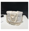 Dettaglio borsa shopper trapuntata bianca con tracolla regolabile su una scrivania - Bianco