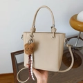 Beige pebble leather bucket bag with knotted handle and brown plush bear charm - Beige