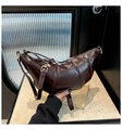 Macro view of dark brown croissant bag featuring glossy finish and segment stitching detail - Brown