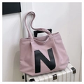 Dettaglio della borsa tote in tela rosa con patch lettera N nera su una valigia - Rosa