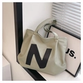 Dettaglio della borsa tote in tela verde salvia con toppa in pelle N e interno capiente - Verde