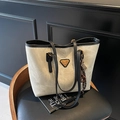 Sac cabas gris beige minimaliste avec brides noires et nœud à franges sur chaise - Avec Pendentif / Beige et noir