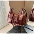 Detail of burgundy crescent shoulder bag with metallic buckle pocket and leather texture - Red