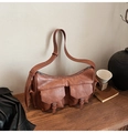 Gros plan d'un sac bandoulière vintage marron en similicuir avec poches à boucle sur bois - Marron