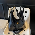 Classic black leather hobo bag with gold triangle logo on a white spotted chair - Black