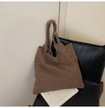 Detail of deep brown knit tote bag showing thick texture on a black leather chair - Brown
