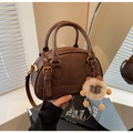 Detail of dark brown leather Boston bag featuring gold hardware and a cute lion plush charm - With Charm / Brown