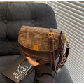 Detail of retro saddle bag with crocodile texture flap and gold lock in dark brown - With Charm / Coffee
