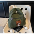 Detalle de mochila de pana verde con bordado de oso y un bonito colgante decorativo - Verde