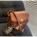 Detail of vintage brown saddle bag with crocodile embossing and golden metal clasp - With Charm / Brown