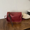 Dark red leather crossbody bag with peanut charm and golden zipper on wood table - With Pendant / Red
