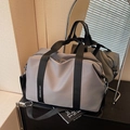 Graue Reisetasche aus Nylon mit schwarzen Tragegurten und Schultergurt in stilvoller Umgebung - Grau