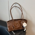 Sac fourre-tout marron foncé brillant avec fines bandoulières et pompon blanc décoratif - café