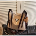 Vue détaillée du sac beige et marron avec breloque ours sur des livres décoratifs - Crème Café Avec Pendentif