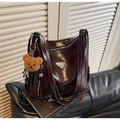Détail d'un grand sac cabas marron brillant avec plusieurs sangles et un ours en peluche - Café avec Pendentif