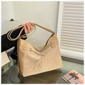Detailed view of khaki large hobo bag with metal eyelets and decorative straps on glass - Khaki