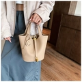 Detail of beige lychee pattern bucket bag featuring gold padlock and smiley charm - Khaki