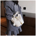 Detailed macro view of cream lychee-textured leather bucket bag with gold metal hardware - White