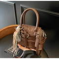 Vue détaillée du sac Boston en cuir marron brillant avec charm raquette et fermetures argentées - Avec Pendentif / café