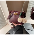 Detail of burgundy leather handbag featuring golden metal buckle and cherry charm - Burgundy