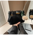 Detail of black leather handbag with gold buckle and plush green leaf charm accessory - Black