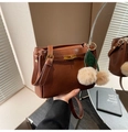 Macro view of brown leather handbag with metal turn-lock and cherry pom-pom charm - Brown