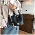 Close-up of black lychee grain leather bucket bag with gold padlock and buckle details - Black