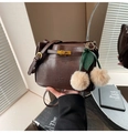 Detail of dark brown leather handbag with gold twist lock and cherry fur pompom charm - Brown