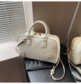 Detalle de bolso Boston crema con textura de cuero fino y herrajes de metal dorado - Blanco Roto