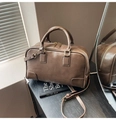 Detalle de un bolso Boston de cuero marrón oscuro con cremalleras doradas de lujo - Marrón