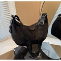 Detail of black nylon dumpling bag featuring wide branded strap and smooth zipper texture - Black