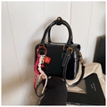 Detail of black leather Boston bag featuring white contrast stitching and gold hardware - Black with Pendant