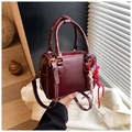 Detail of burgundy Boston bag with white stitching, dual handles and woven rope charm - Red with Pendant