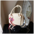 Detailed close-up of cream Boston bag with gold rings and decorative floral pendant charm - Cream White With Pendant