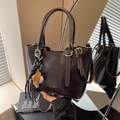 Bolso tipo cubo de cuero marrón oscuro brillante con colgante de béisbol y bandolera - Café con Colgante