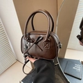 Sac bowling rétro marron foncé avec finition brillante et nœud dans un cadre moderne - Café avec Pendentif