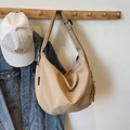 Große beige Segeltuch-Umhängetasche in Halbmondform an einem Holzkleiderbügel - Khaki