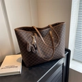 Bruine monogram draagtas met lederen riemen en een vlinderhanger in lifestyle-setting - Koffie (Met Hanger)