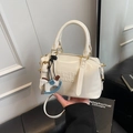 Cream white Boston bag with embossed lettering and horse pendant detail shown handheld - White with Pendant