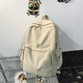 Minimalist cream canvas backpack with front zipper pocket on metal display rack - Off-white