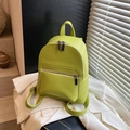 Chic lime green pebbled leather backpack with silver zippers on a white blazer background - Green