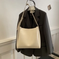 Bolso tote grande de cuero PU beige con correa ancha sobre una chaqueta de traje oscura - Blanco