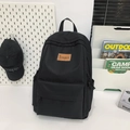 Minimalist black nylon backpack for women featuring a premium brown leather logo tag - Black