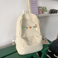 Minimalist beige backpack with colorful pom-pom charms on a green wooden bench - White Without Pendant
