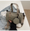 Gros plan d'un sac cylindrique en toile grise avec mini pochette ronde et bandoulière large - Taille unique / Vert