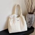 Cream quilted tote bag with lace bow decoration and LOVE label on black shelf - Off White